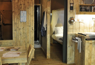 Interno della tenda Safari al Lago Idro Glamping Boutique in Italia, con cucina e arredi in legno.