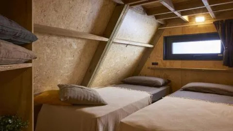 Twee enkele bedden in een sfeervolle houten kamer bij A Luxury, Chianti Glamping Resort, Italië.