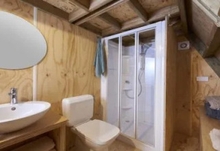 Badkamer in hout met wc, lavabo, douche en spiegel in A Luxury, Chianti Glamping Resort, Italië.