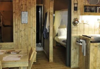 Gemütliches Safari-Zeltinterieur im Chianti Glamping Resort, Italien, mit Holzdekor und Schlafzimmer.
