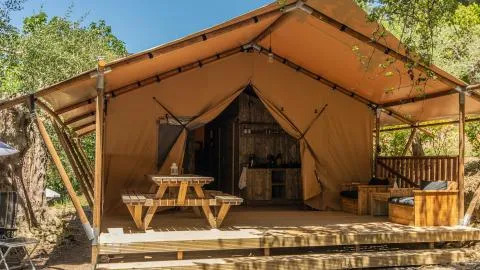 Safari Tenten bij Chianti Glamping Resort in Italië, met houten veranda, picknicktafel en buitenzitjes.