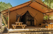 Safari-Zelt „Safari Tenten“ im Chianti Glamping Resort Italien, mit Holzterrasse und Picknicktisch.