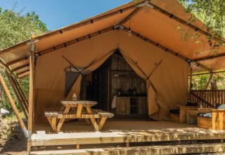 Safari Tenten bij Chianti Glamping Resort in Italië, met houten veranda, picknicktafel en buitenzitjes.