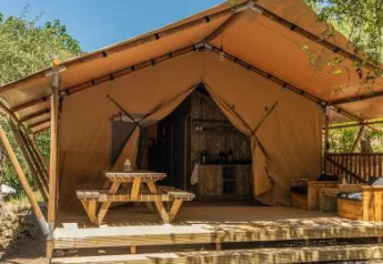 Safari Tenten bij Chianti Glamping Resort in Italië, met houten terras, picknicktafel en zitbankjes buiten.
