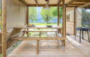 Buiten eetruimte bij de 'Air Dreamer' safaritent op Lago Idro Glamping Boutique in Italië, met houten tafels.