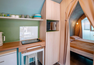 Binnenaanzicht van een Coco Suite pod bij Lago Idro Glamping Boutique met kitchenette en knusse slaapkamer.