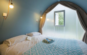 Slaapkamer in een Coco Suite pod op Lago Idro Glamping Boutique in Italië, met bed en raam.