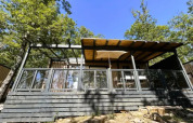 'Cottage Next' L Evo im Chianti Glamping Resort in Italien, moderner Holzbau mit Terrasse zwischen Bäumen.