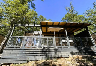 Vue du 'Cottage Next' L Evo au Chianti Glamping Resort, Italie, un lodge moderne en bois entouré d’arbres.