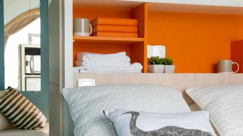 Knusse safaritent met oranje wand, kussens, handdoeken en mokken in Chianti Glamping Resort, Italië.