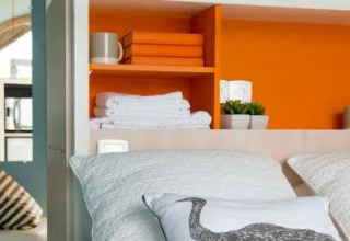 Knusse safaritent met oranje wand, kussens, handdoeken en mokken in Chianti Glamping Resort, Italië.