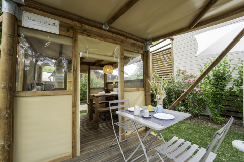 Buitenontbijttafel bij de safaritent 'Airstay' aan Lago Idro Glamping Boutique in Italië, tussen struiken.