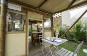 Buitenontbijttafel bij de safaritent 'Airstay' aan Lago Idro Glamping Boutique in Italië, tussen struiken.