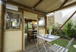 Buitenontbijttafel bij de safaritent 'Airstay' aan Lago Idro Glamping Boutique in Italië, tussen struiken.