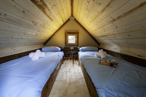 Twee enkele bedden met lichtblauw beddengoed in Airstay safaritent, Lago Idro Glamping Boutique, Italië.