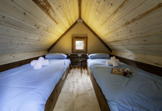 Twee enkele bedden met lichtblauw beddengoed in Airstay safaritent, Lago Idro Glamping Boutique, Italië.