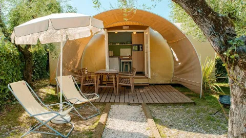 Tente safari Coco Suite au Chianti Glamping Resort en Italie, terrasse avec chaises longues et parasol.