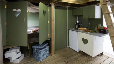Binnenkant van een Air Lodge bij Lago Idro Glamping Boutique, Italië, met groene keuken en slaapplaats.