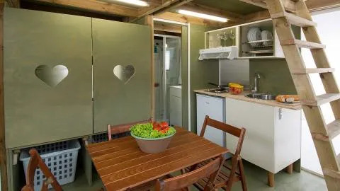 Interieur van de Air Lodge bij Lago Idro Glamping Boutique in Italië met keukenhoek, houten tafel en trap.