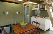 Interieur van de Air Lodge bij Lago Idro Glamping Boutique in Italië met keukenhoek, houten tafel en trap.