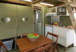 Interieur van de Air Lodge bij Lago Idro Glamping Boutique in Italië met keukenhoek, houten tafel en trap.