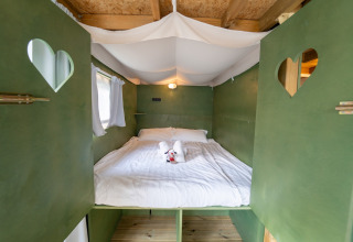 Gezellige Air Lodge slaapcabine met groene wanden en hartvormige ramen bij Lago Idro Glamping Boutique in Italië.