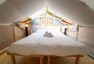 Gezellige slaapkamer met groot bed in de Air Lodge aan Lago Idro Glamping Boutique, Italië.
