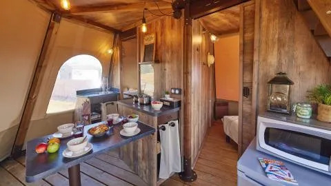 Interno del Tipi Lodge al Lago Idro Glamping Boutique in Italia, con arredi in legno e zona pranzo accogliente.