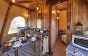 Interno del Tipi Lodge al Lago Idro Glamping Boutique in Italia, con arredi in legno e zona pranzo accogliente.