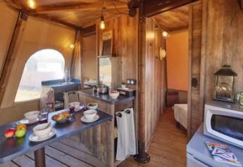 Interior del Tipi Lodge en Lago Idro Glamping Boutique, Italia, con decoración de madera y área de comedor acogedora.