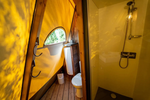 Bagno moderno in una tenda Tipi, con illuminazione gialla, doccia, wc e finestra al Lago Idro Glamping Boutique.