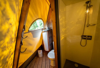 Bagno moderno in una tenda Tipi, con illuminazione gialla, doccia, wc e finestra al Lago Idro Glamping Boutique.