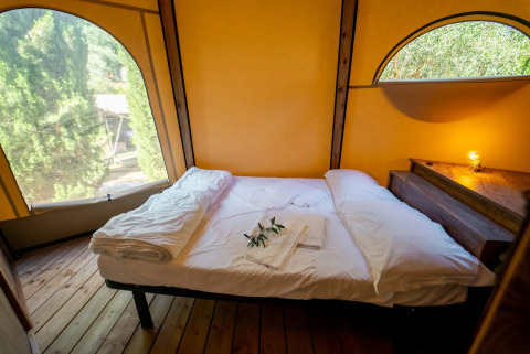 Vista interna di un letto accogliente nel Tipi Lodge al Lago Idro Glamping Boutique in Italia.