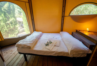 Vista interna di un letto accogliente nel Tipi Lodge al Lago Idro Glamping Boutique in Italia.