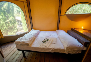 Vista interior de una cama acogedora en la tienda Tipi Lodge en Lago Idro Glamping Boutique, Italia.