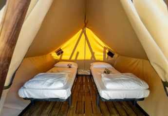 Vista interior de la tienda Tipi Lodge con dos camas individuales en Lago Idro Glamping Boutique, Italia.