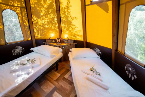 Interno della tenda Tipi Lodge con due letti singoli al Lago Idro Glamping Boutique in Italia.
