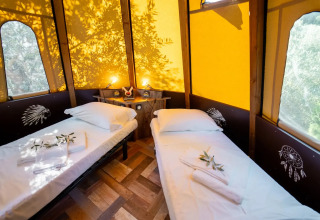 Interno della tenda Tipi Lodge con due letti singoli al Lago Idro Glamping Boutique in Italia.