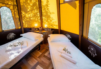 Interior de tienda tipi Tipi Lodge con dos camas individuales en Lago Idro Glamping Boutique, Italia.