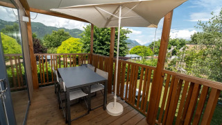 Terras met houten vloer en eettafel bij Next XL Loggia chalet, zicht op bergen en omringend groen.