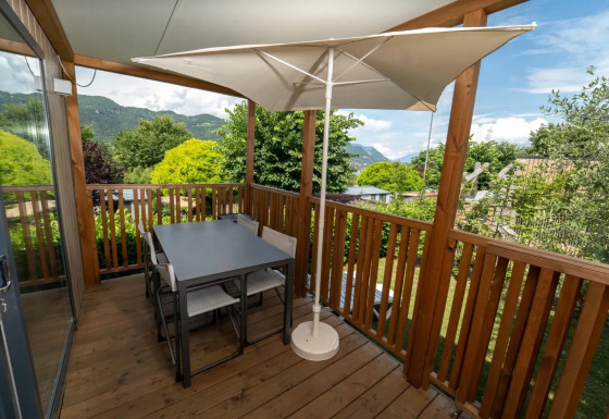 Terras met houten vloer en eettafel bij Next XL Loggia chalet, zicht op bergen en omringend groen.