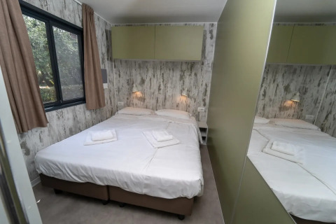Slaapkamer in de Next XL Loggia chalet aan Lago Idro Glamping Boutique in Italië met dubbel bed en spiegel.