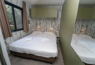 Slaapkamer in de Next XL Loggia chalet aan Lago Idro Glamping Boutique in Italië met dubbel bed en spiegel.