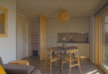 Zona soggiorno e cucina moderna nella Dome House al Wecamp Reserva Alecrim, Portogallo, con arredi in legno.