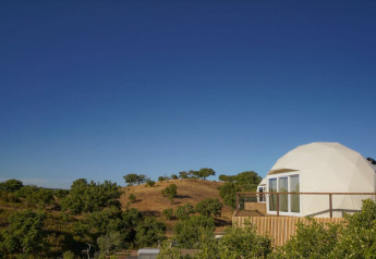 Dome House presso Wecamp Reserva Alecrim in Portogallo con cupola geodetica, terrazza e colline sotto cielo azzurro.