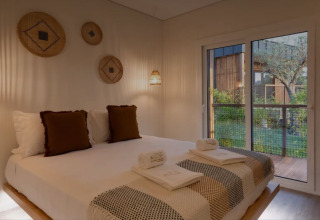 Slaapkamer in Dome House, Wecamp Reserva Alecrim, Portugal, met dubbel bed, sfeerverlichting en terraszicht.