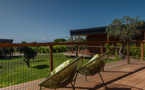 Zicht vanaf de Dome House op Wecamp Reserva Alecrim, Portugal, met moderne stoelen en groene tuin.