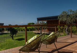 Zicht vanaf de Dome House op Wecamp Reserva Alecrim, Portugal, met moderne stoelen en groene tuin.