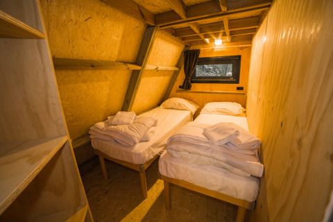 Interieur van de 'A Luxury' safaritent bij Trasimeno Glamping Resort met twee eenpersoonsbedden en houten muren.