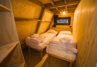 Interieur van de 'A Luxury' safaritent bij Trasimeno Glamping Resort met twee eenpersoonsbedden en houten muren.